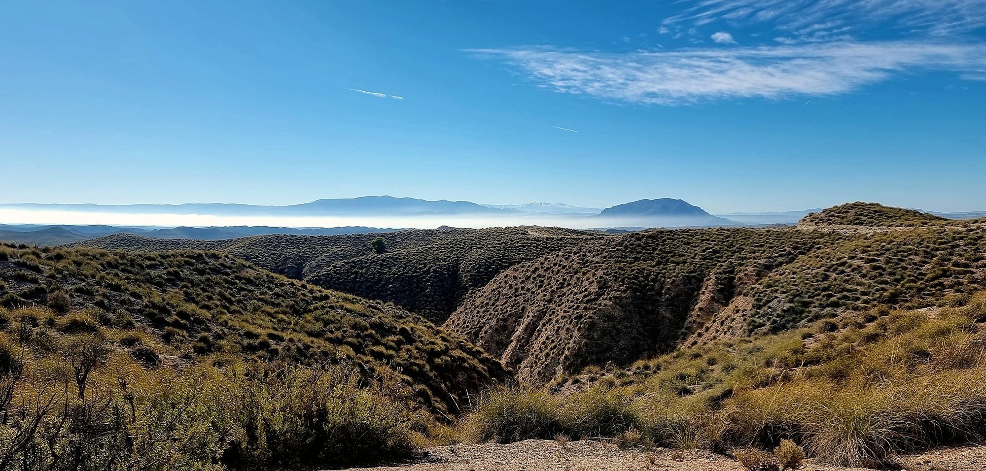 Eroded badlands and distant mountains in the Granada UNESCO Global Geopark