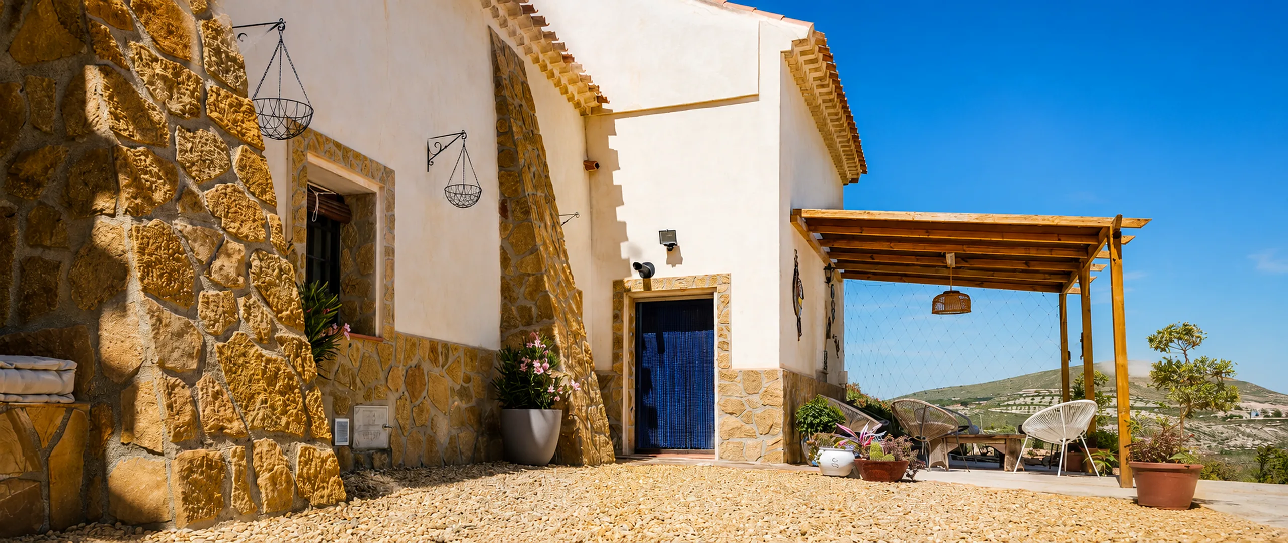 Exterior of Leonard's Lookout cave house with stone walls and shaded terrace in rural Granada