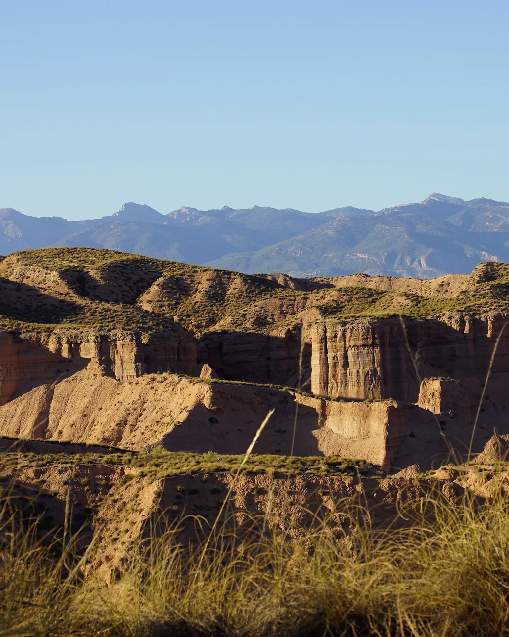 Layered badland cliffs and distant mountains in the Gorafe Desert, Granada Geopark